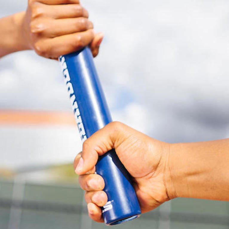 Two UCR runners pass the stick in a relay
